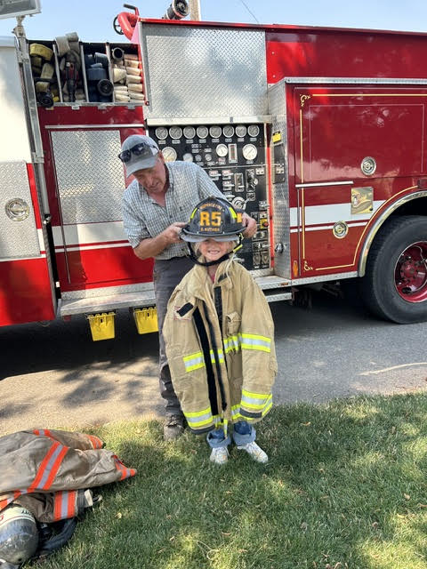 Fire Chief Dave Kuther helps a future firefighter get ready for duty. 